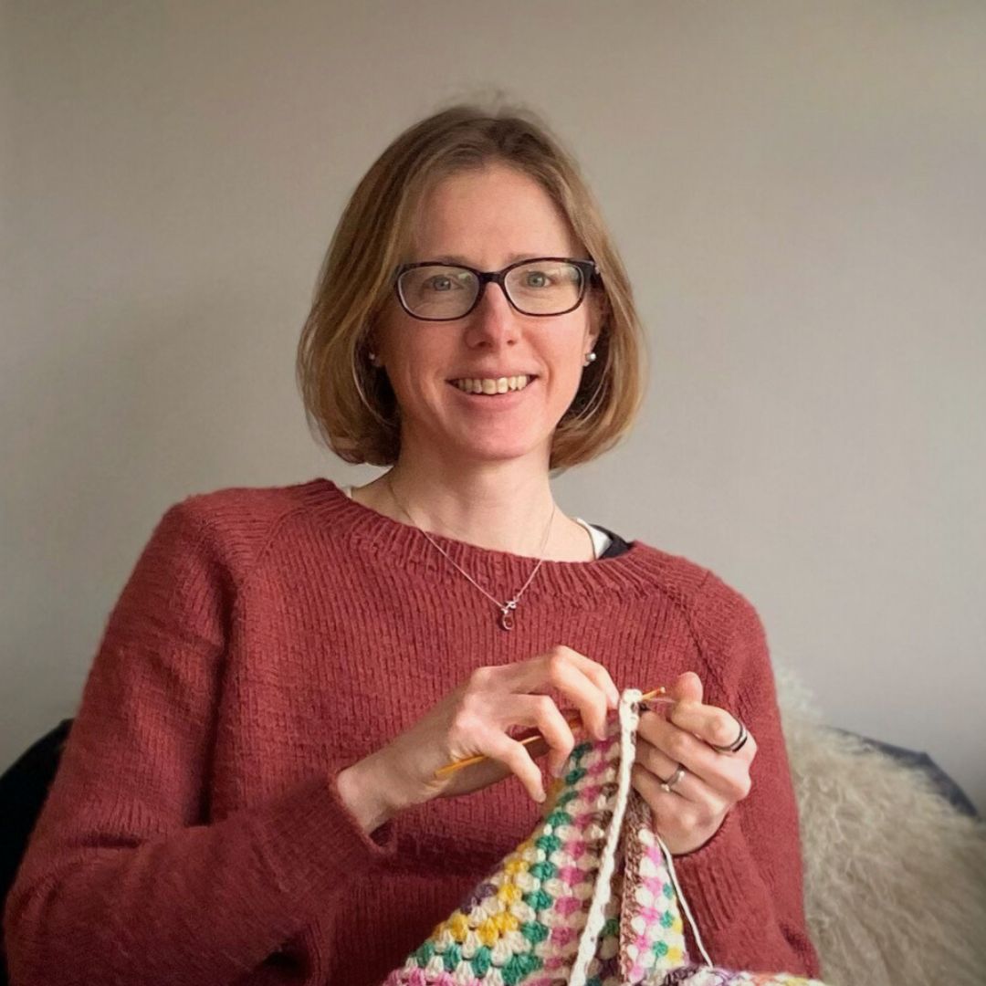 picture of catherine the designer behind catherine crochets, crocheting a blanket
